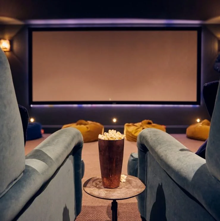 Cinema seats facing a large screen with popcorn on a table