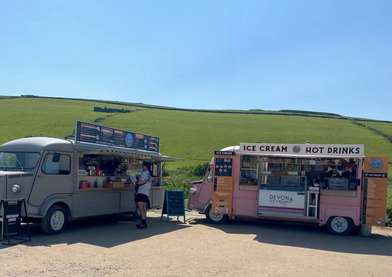 The Gastrobus and pink Treats van parked beside the grass at Bantham