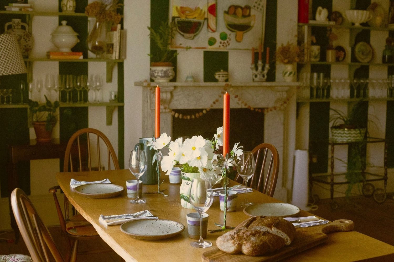A candlelit table with bread and flowers in Glebe House dining room