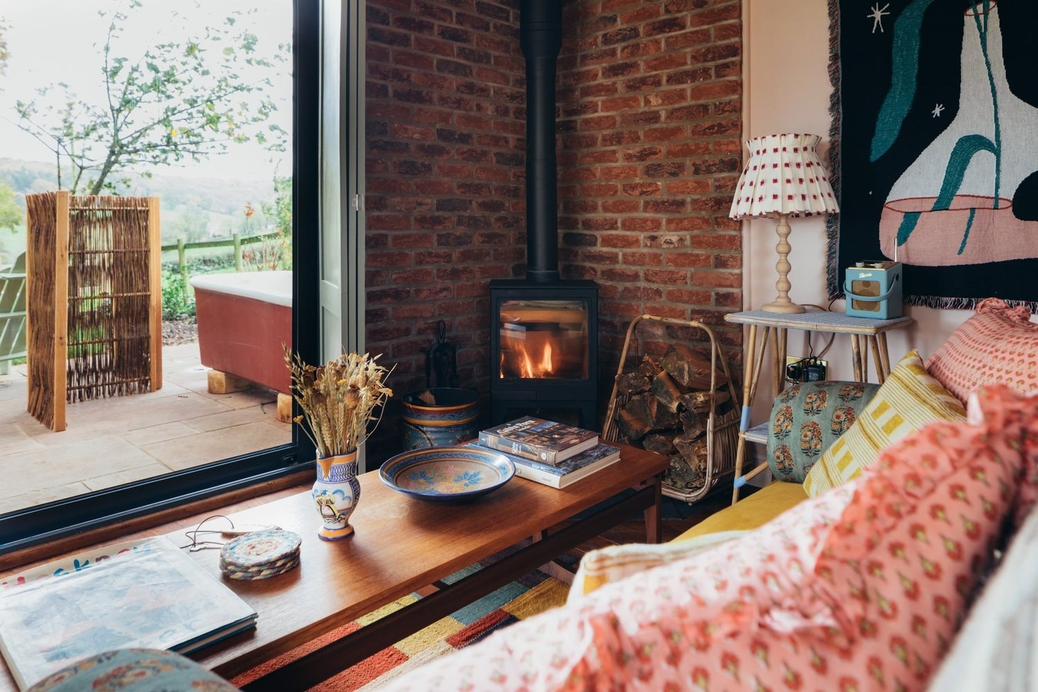 Colourful cushions and a wood burner inside a Glebe House cabin