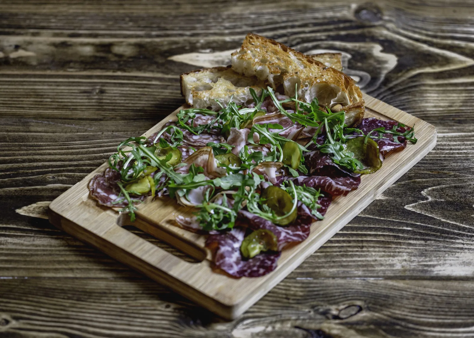 Charcuterie and salad served on a wooden board