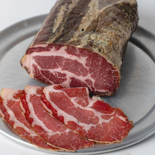 Coppa with several thin slices on a white plate