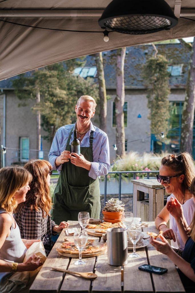 A member of the team serving guests at an outdoor table