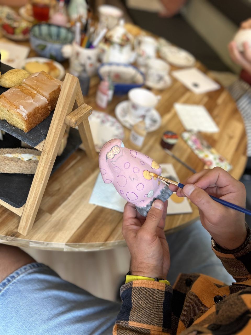 A visitor painting a small ceramic piece