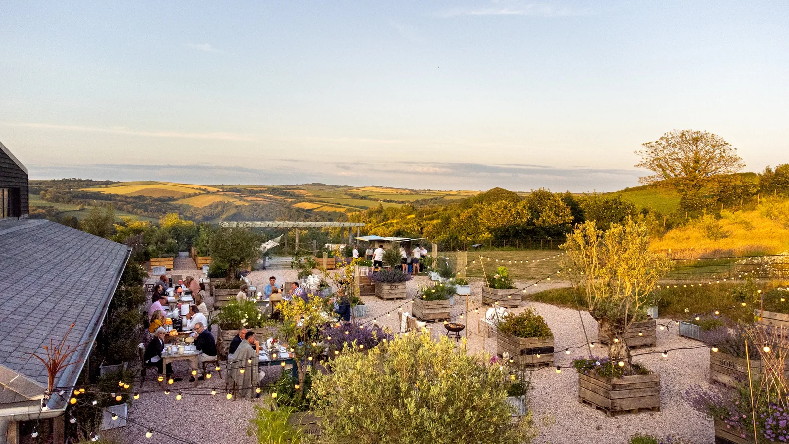 People at tables among planters in the Heron Valley courtyard at sunset