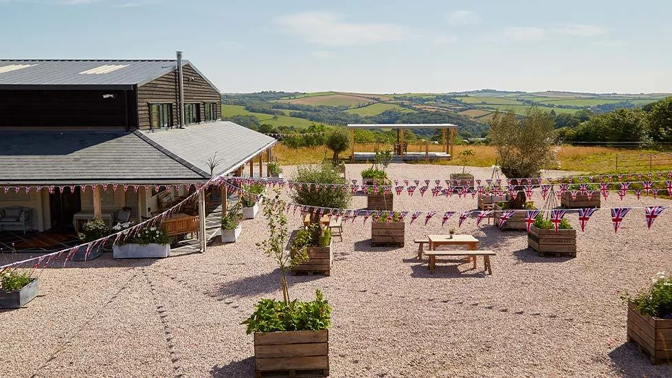 Picnic tables and bunting in Heron Valley courtyard with green hills beyond