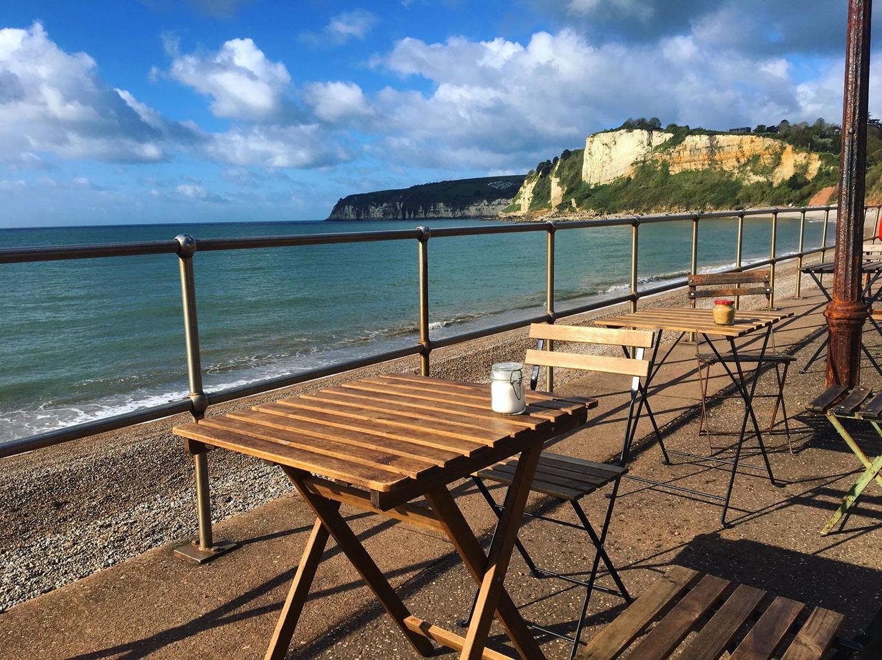 Wooden café tables beside the sea at The Hideaway Seaton