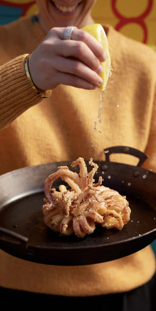 Diner holding a drink beside a plated seafood dish