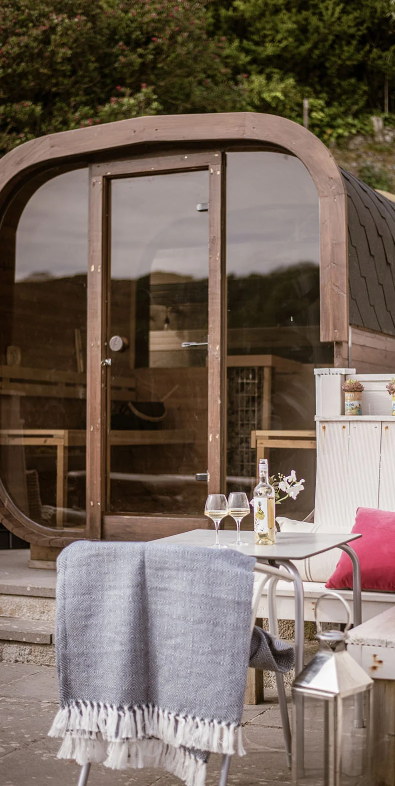 Wooden barrel sauna beside a terrace table