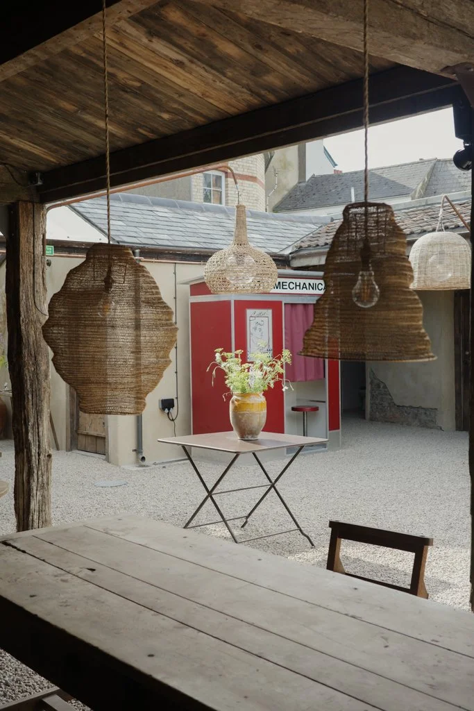 Wooden seating and woven lamps looking into Inba’s courtyard