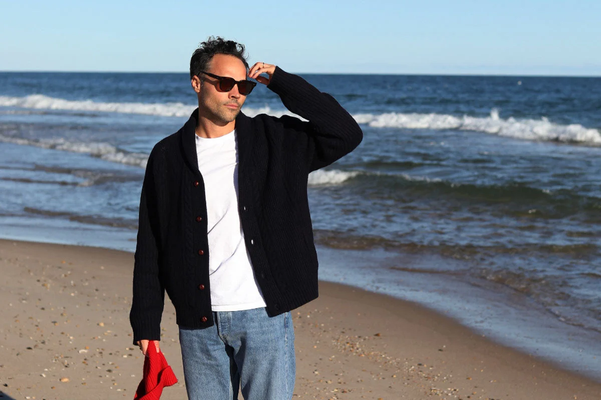 JAM Industries’ official campaign photograph of a model wearing a navy cardigan beside the sea