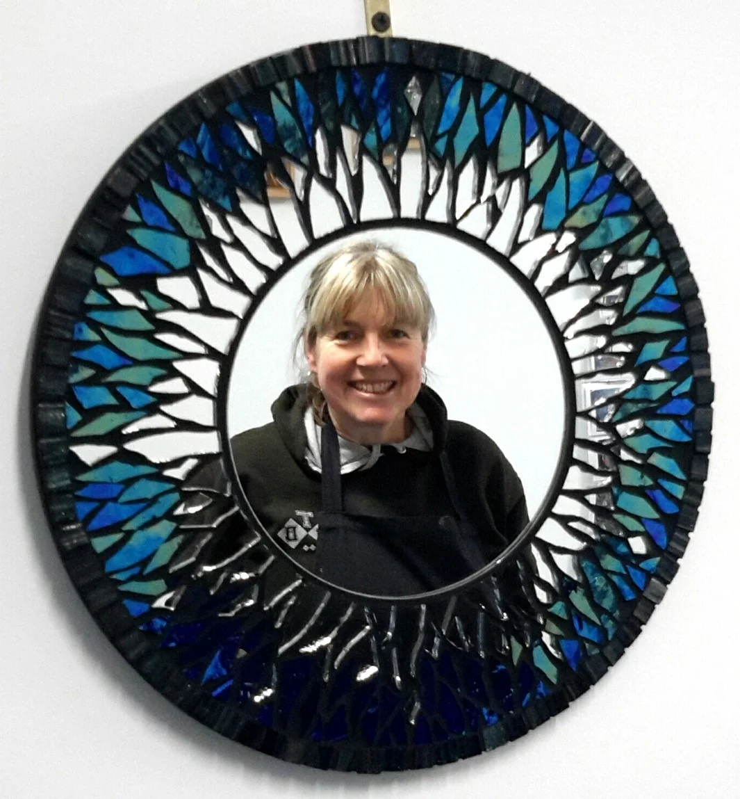 Janet reflected in a circular blue and white mosaic mirror