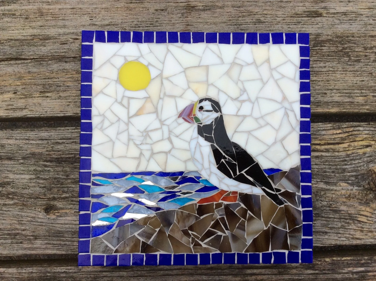 Mosaic picture of a puffin beside the sea