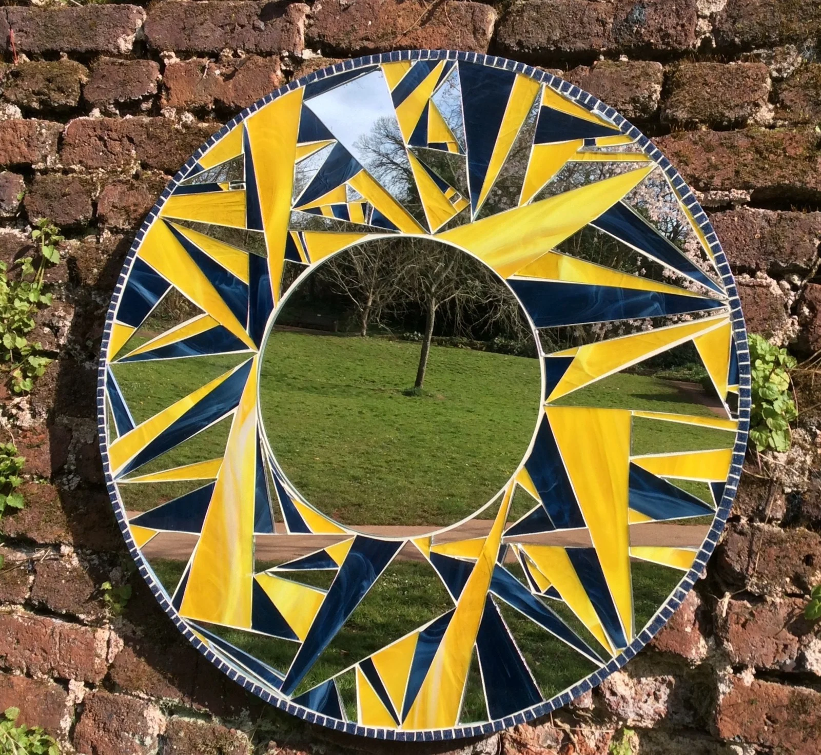 Circular mirror surrounded by yellow and blue mosaic fragments