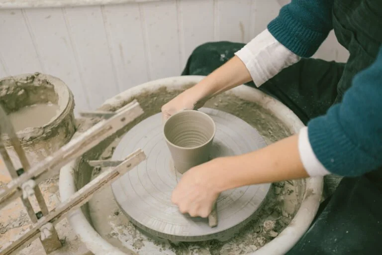 Hands shaping a pot on the wheel at Kitty Ward Pottery
