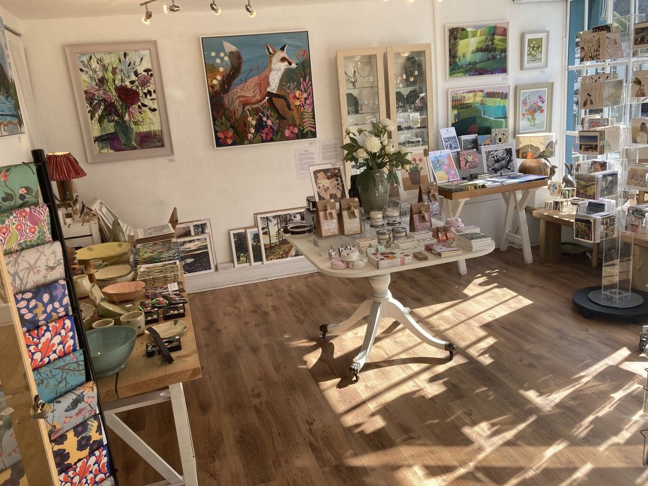Sunlit gallery interior filled with paintings and ceramics