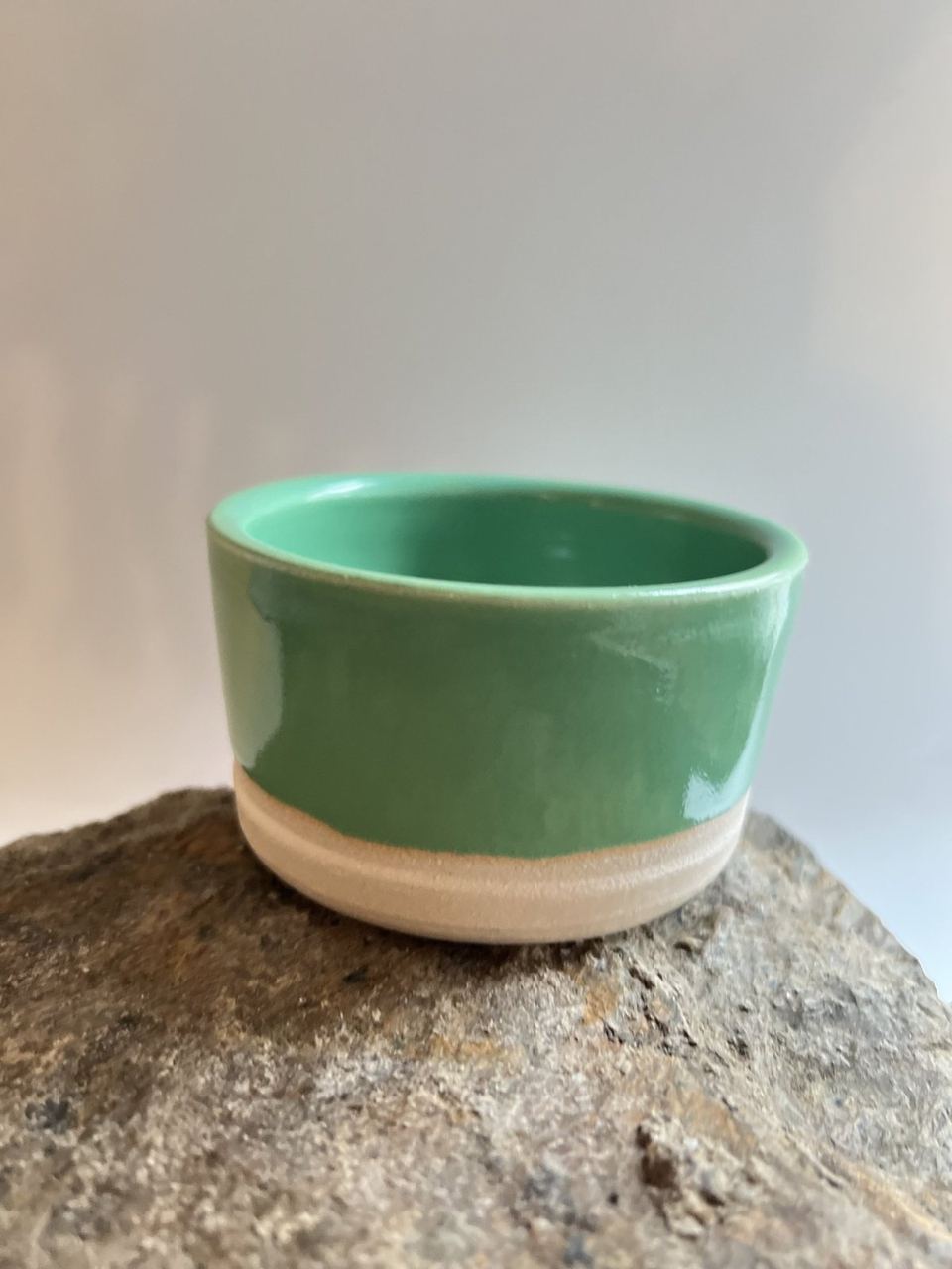 A green glazed ceramic bowl in warm natural light