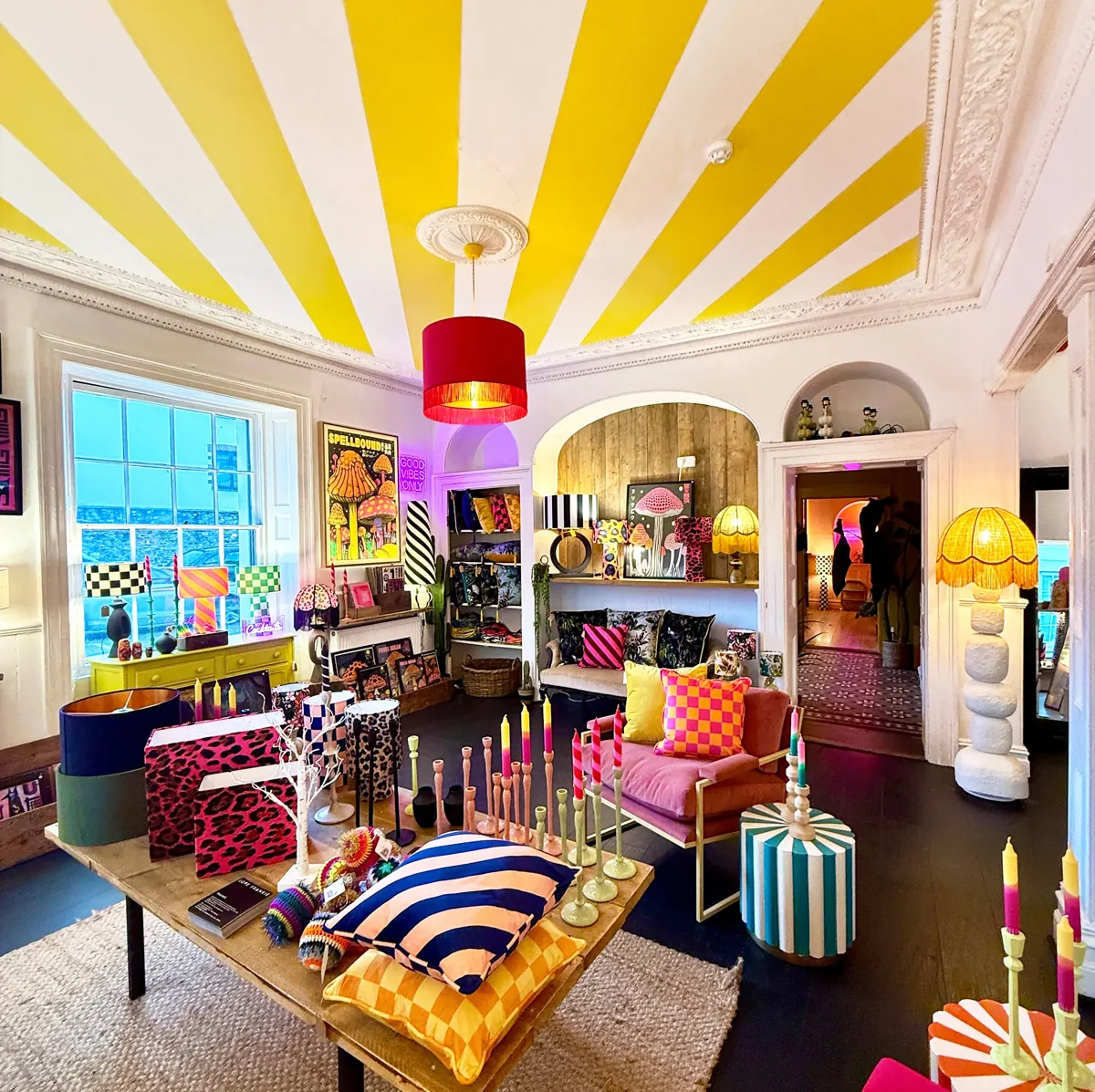 Colourful Love Frankie shop room with a yellow striped ceiling and patterned cushions