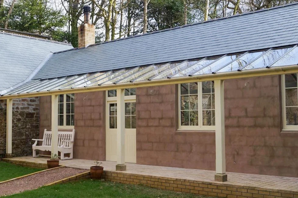 Stone tea-room building with a glass porch and garden benches at Lukesland