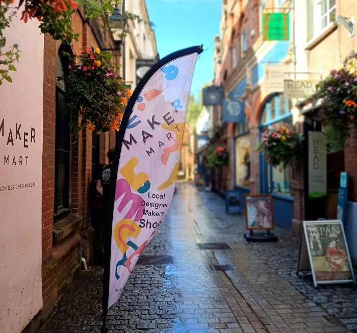 Maker Mart flag beside its entrance on Exeter’s cobbled Gandy Street