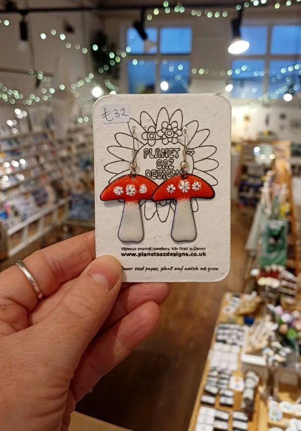 Red spotted mushroom earrings displayed on a card at Maker Mart