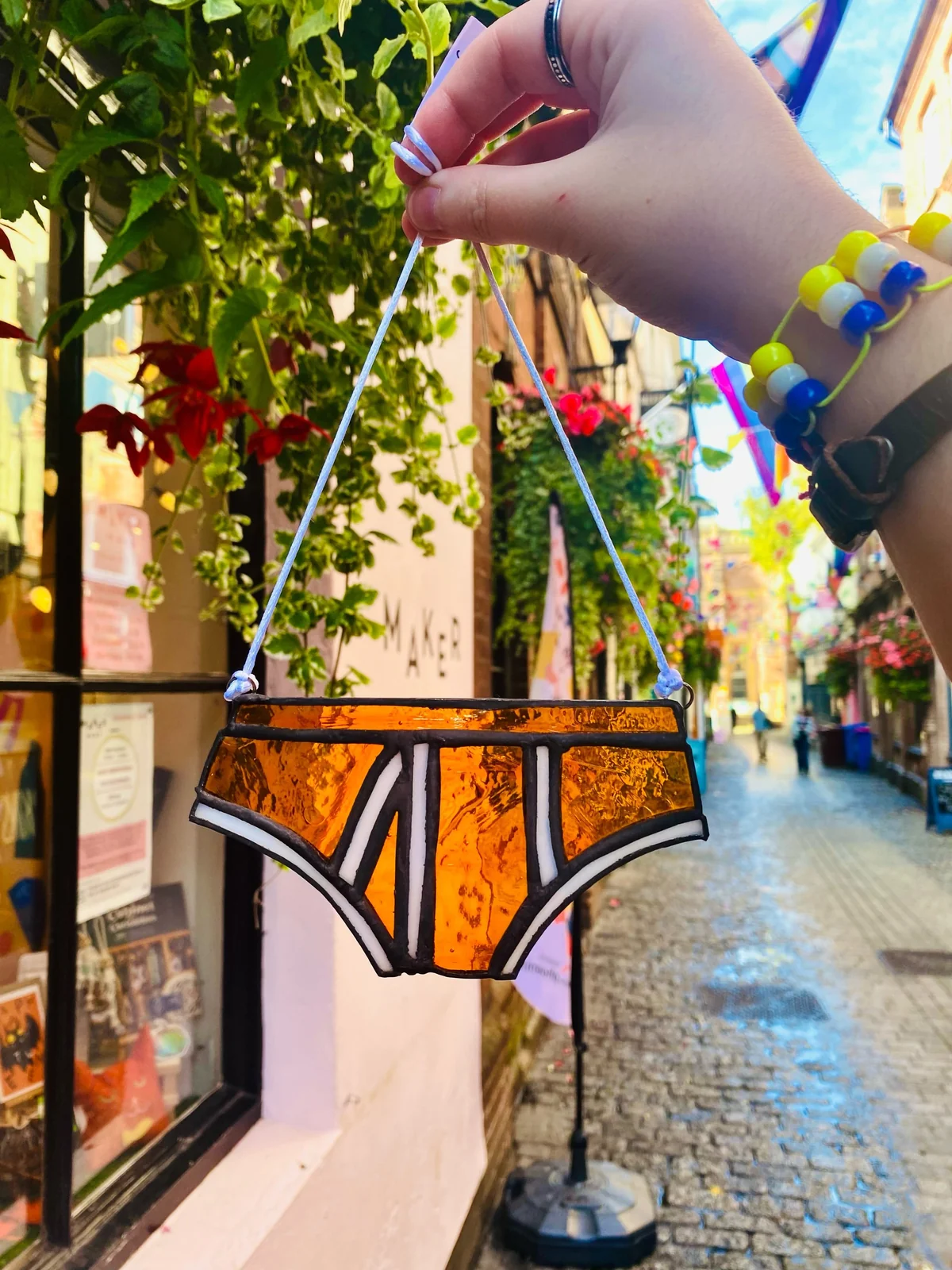 A small stained-glass hanging held outside Maker Mart