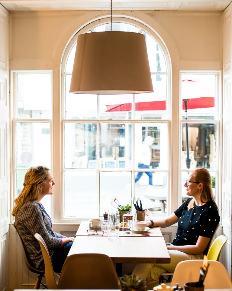 Two customers seated at a window table inside Mangetout café