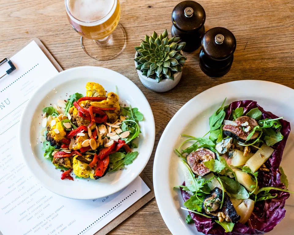 Two colourful salad plates on a wooden table at Mangetout