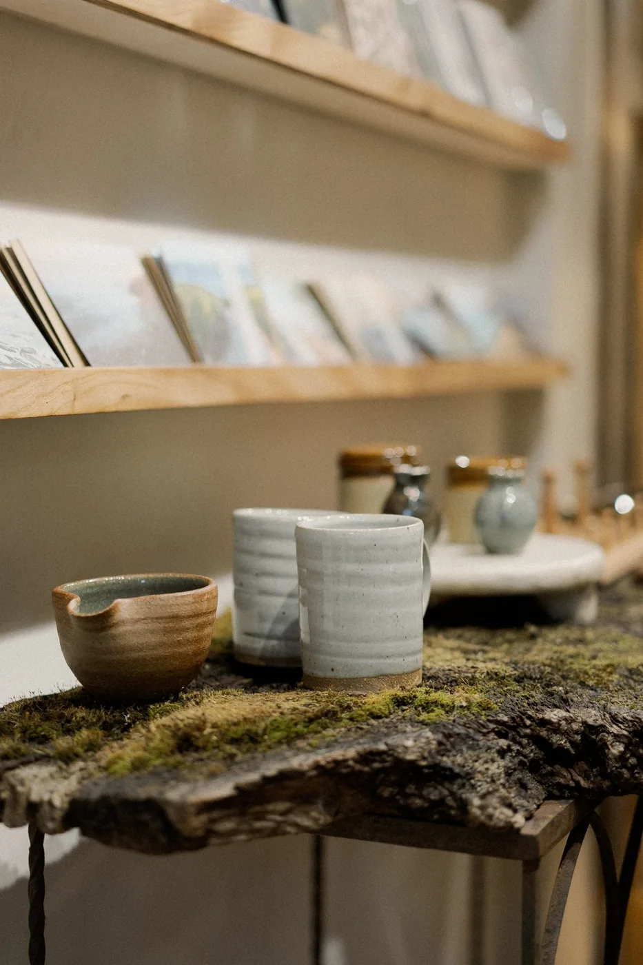 Handmade bowls and mugs displayed on a textured shop table