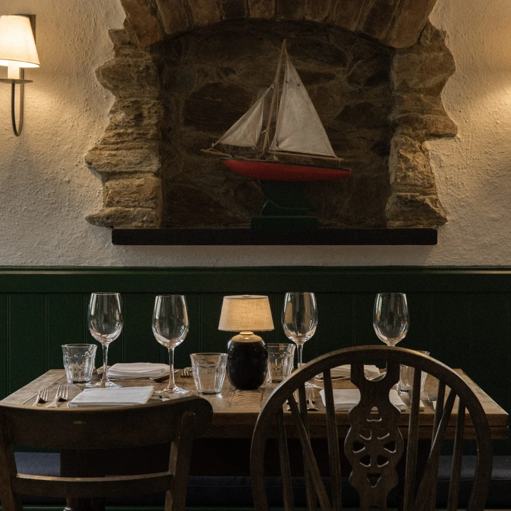 Table laid beneath a model sailing boat in a stone recess