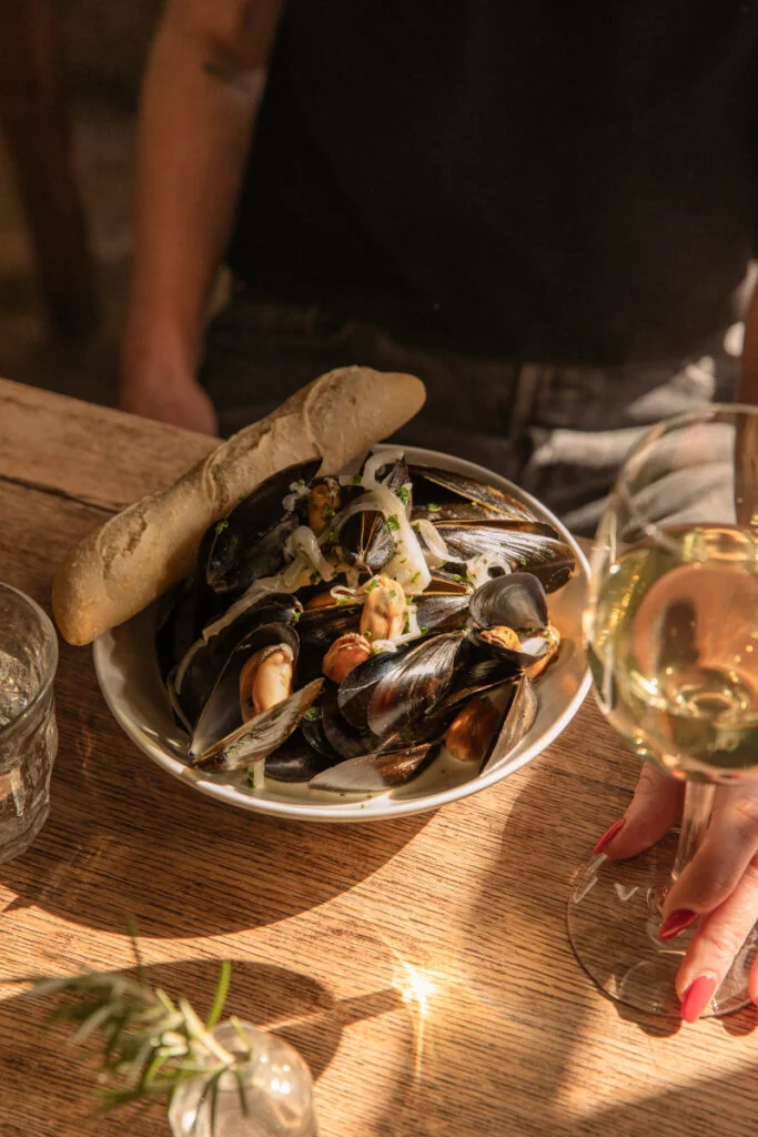 A bowl of mussels with bread on a dining table