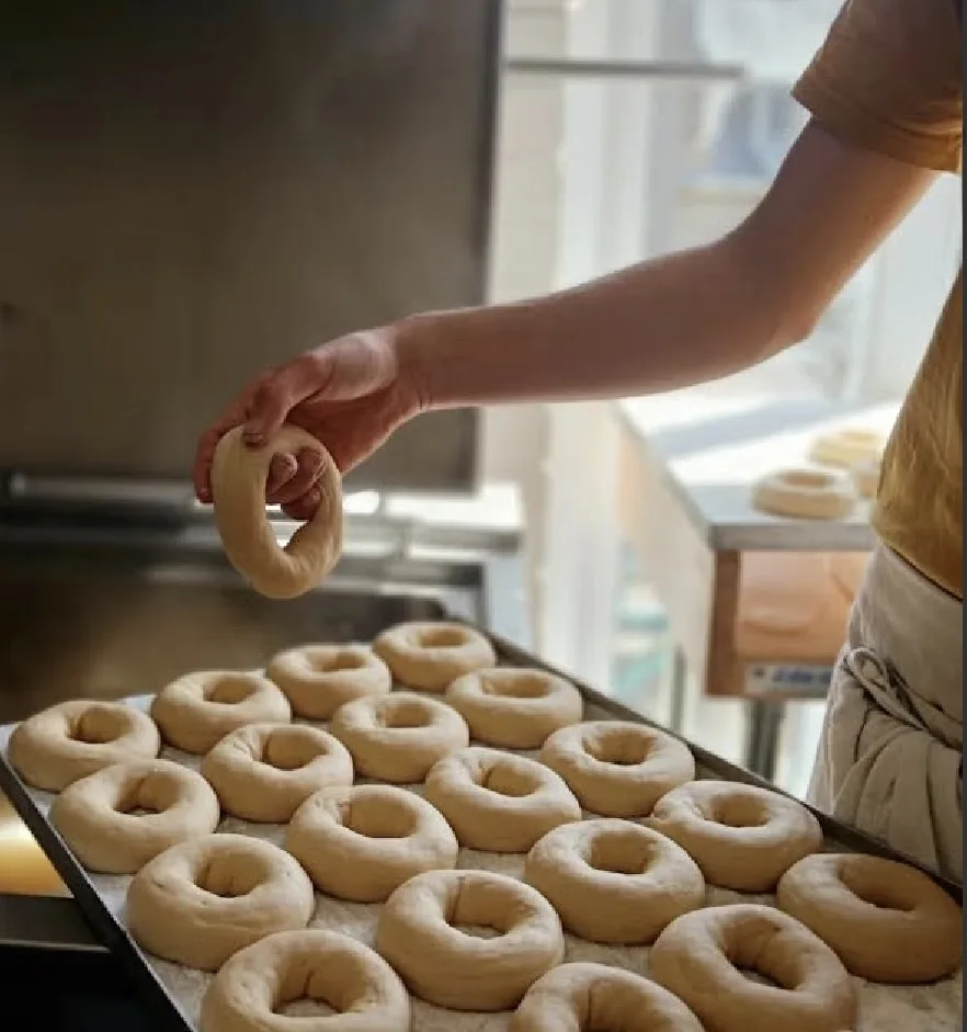 A baker shaping bagels at Montreal Style Bagels