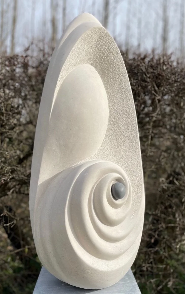 Tall pale stone sculpture with sweeping carved curves