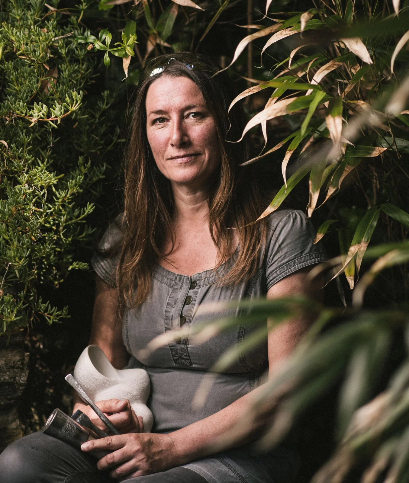 Nicola Axe seated outdoors holding a small sculpture