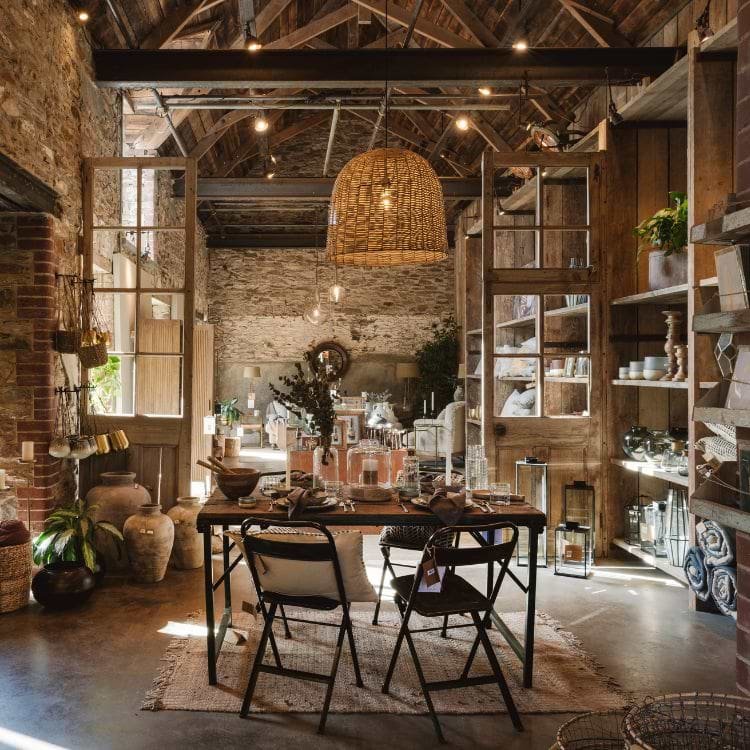 Rustic dining furniture and pendant lighting at the entrance to Nkuku’s Devon store