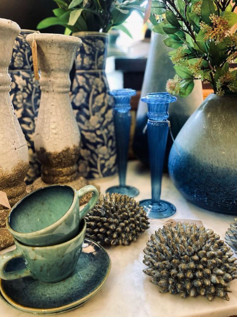 A green cup, blue glass and woven cushions displayed in the Ashburton shop