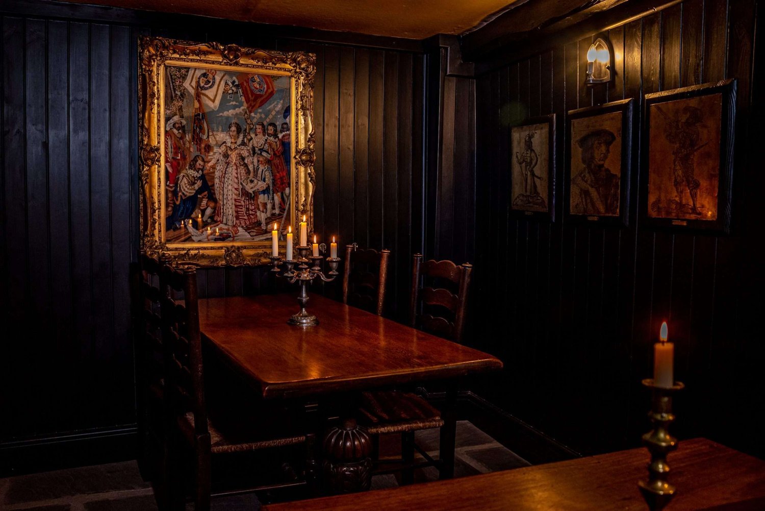Dark panelled dining room with candlelit tables and framed artwork