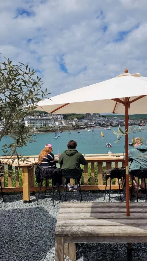 Visitors seated beneath a parasol looking across the estuary