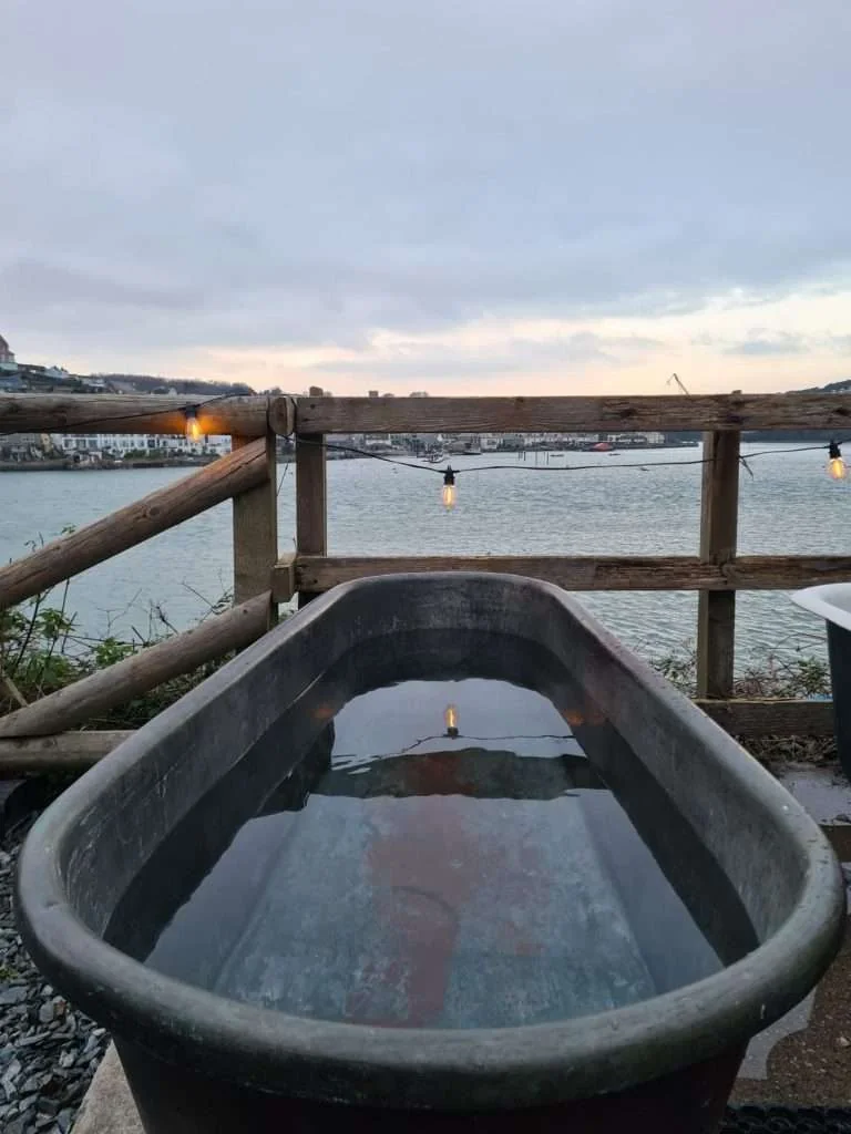 Outdoor tub beside a railing overlooking the harbour at dusk