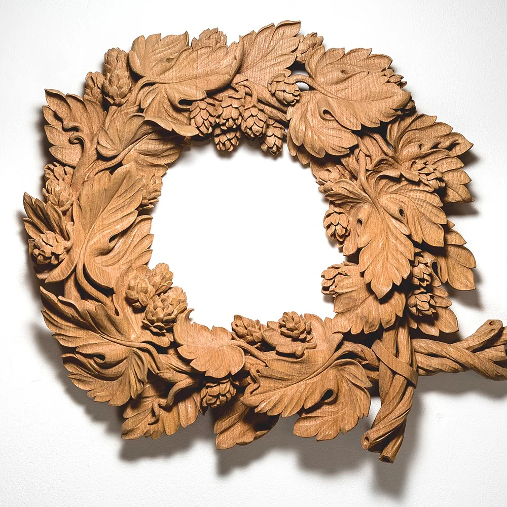 An intricately carved wooden wreath of leaves and hops