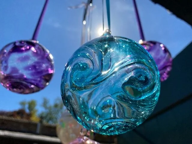 Blue and purple glass ornaments hanging in sunlight