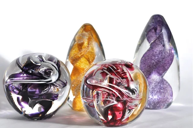 Colourful sculptural glass paperweights grouped together