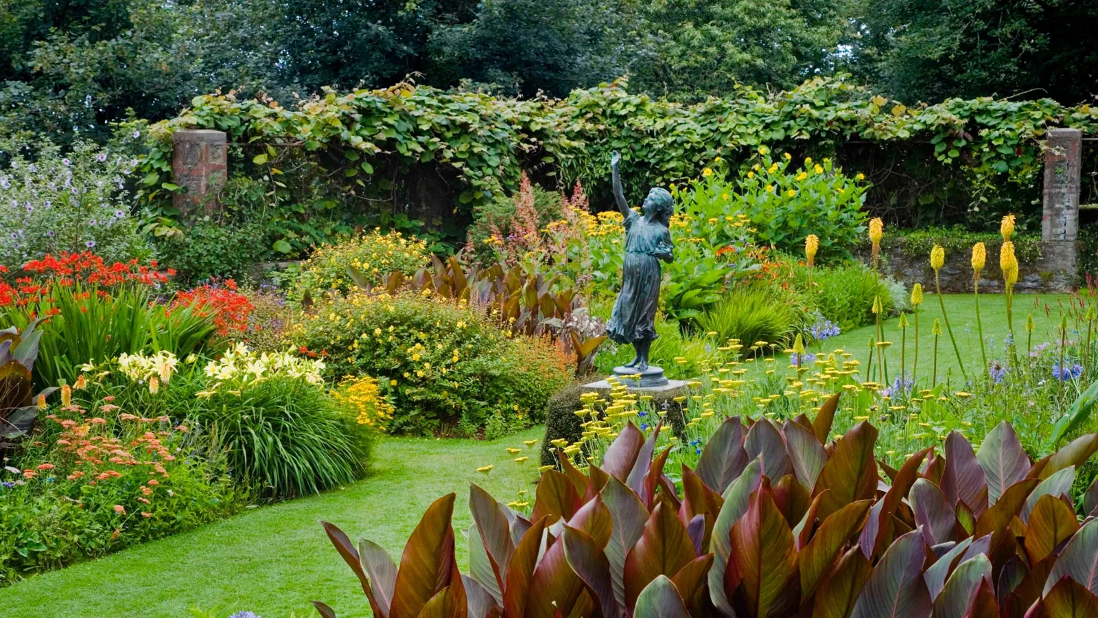Colourful flower borders around a sculpture in the garden