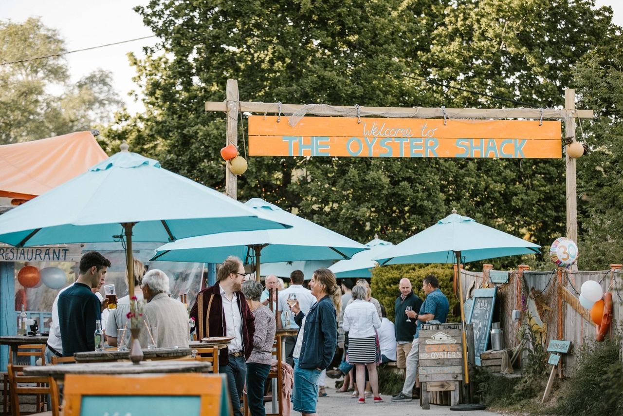 Turquoise umbrellas and the entrance sign at The Oyster Shack