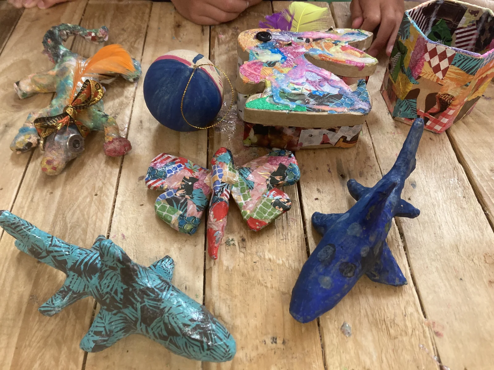 Colourfully decorated papier-mâché animals and birds on a worktable