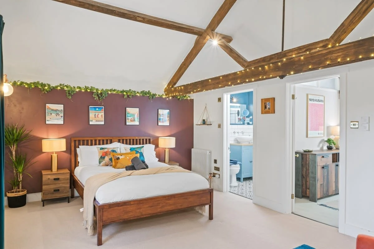 Vaulted bedroom with exposed beams and a burgundy wall