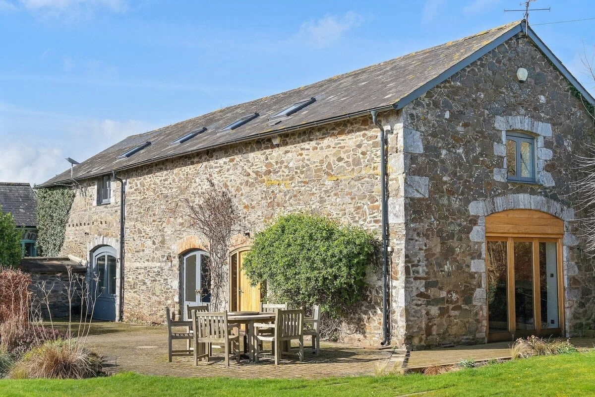 Stone barn exterior with a garden table on the lawn