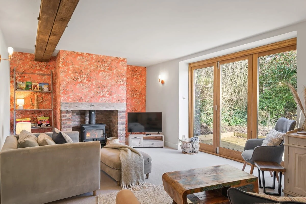 Sitting room with wood burner, patterned wall and garden doors