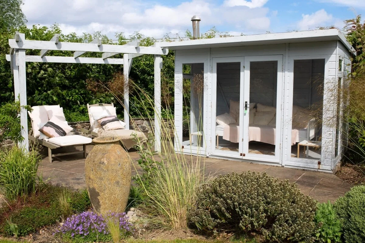 Garden summerhouse beside a pergola and outdoor seating