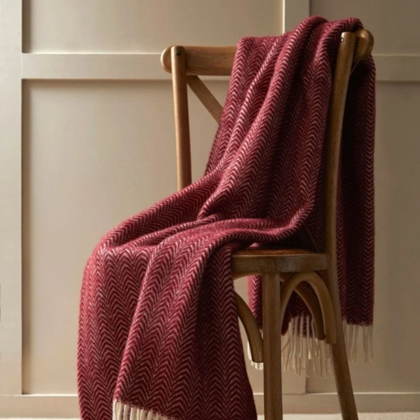 A burgundy wool throw draped over a wooden chair